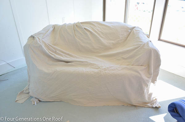 pottery barn white slipcover over old couch, cement floor, pool house 