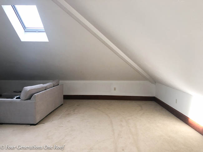 empty loft with slanted ceiling, sky light window, beige carpet and sectional 