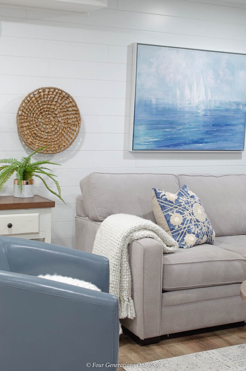 white plank wall, grey couch, blue medallion pillow, seagrass wall accent, coastal wall art