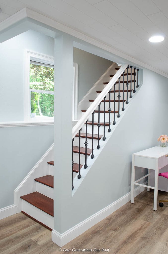 basement stairs with iron balusters and black knuckles, harvest oak vinyl plank flooring, blue walls