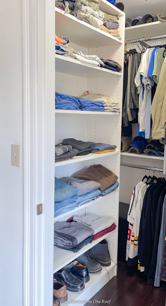 mens walk in closet with white wood shelves and hanging rods