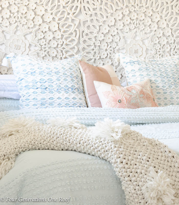 light blue and green layered bedding on king bed