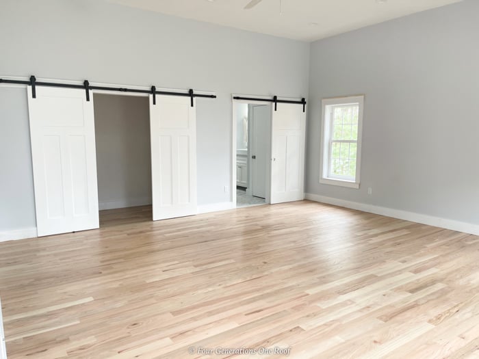 3 white sliding interior doors to bathroom and closet, white oak floors, blue walls