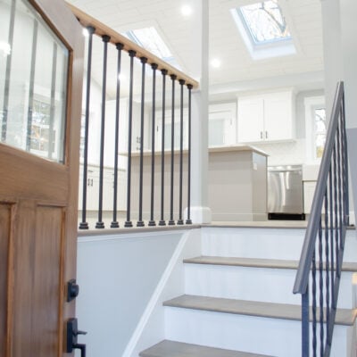 open split level stairway with black metal balusters, blue walls, vaulted ceiling
