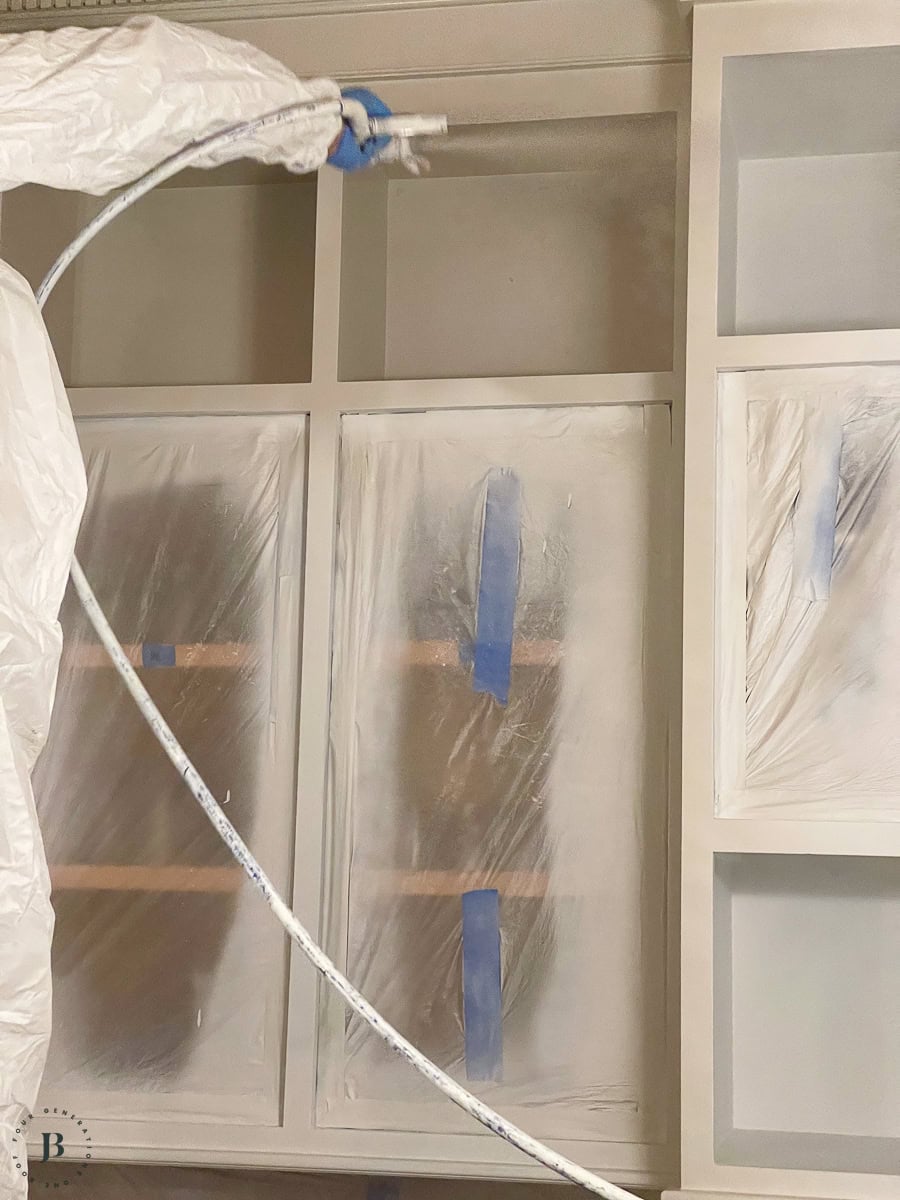 man painting kitchen cabinets gray with Graco magnum paint sprayer