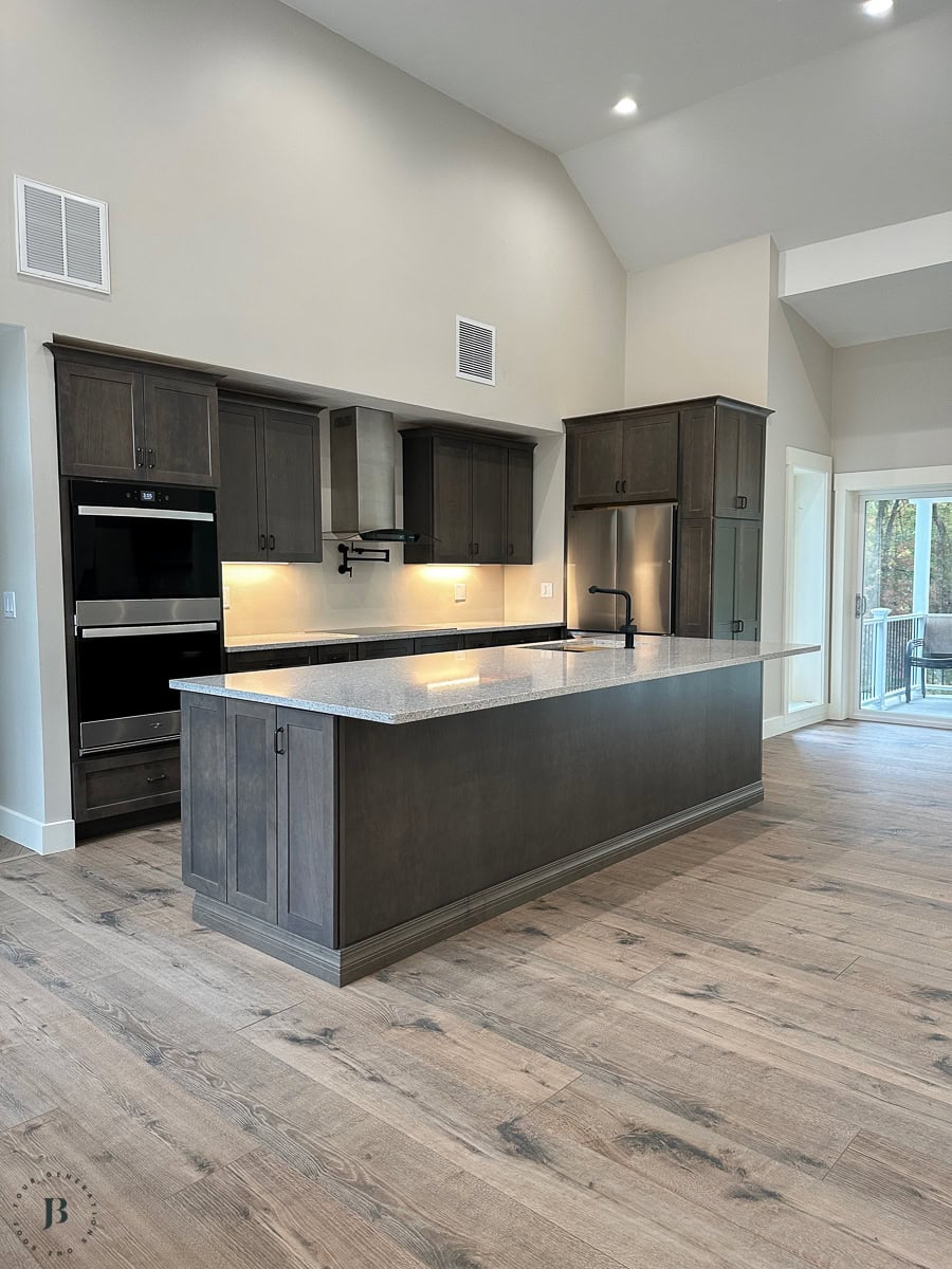 Multigenerational house plans kitchen featuring wide plank flooring and dark brown cabinetry for compound family living