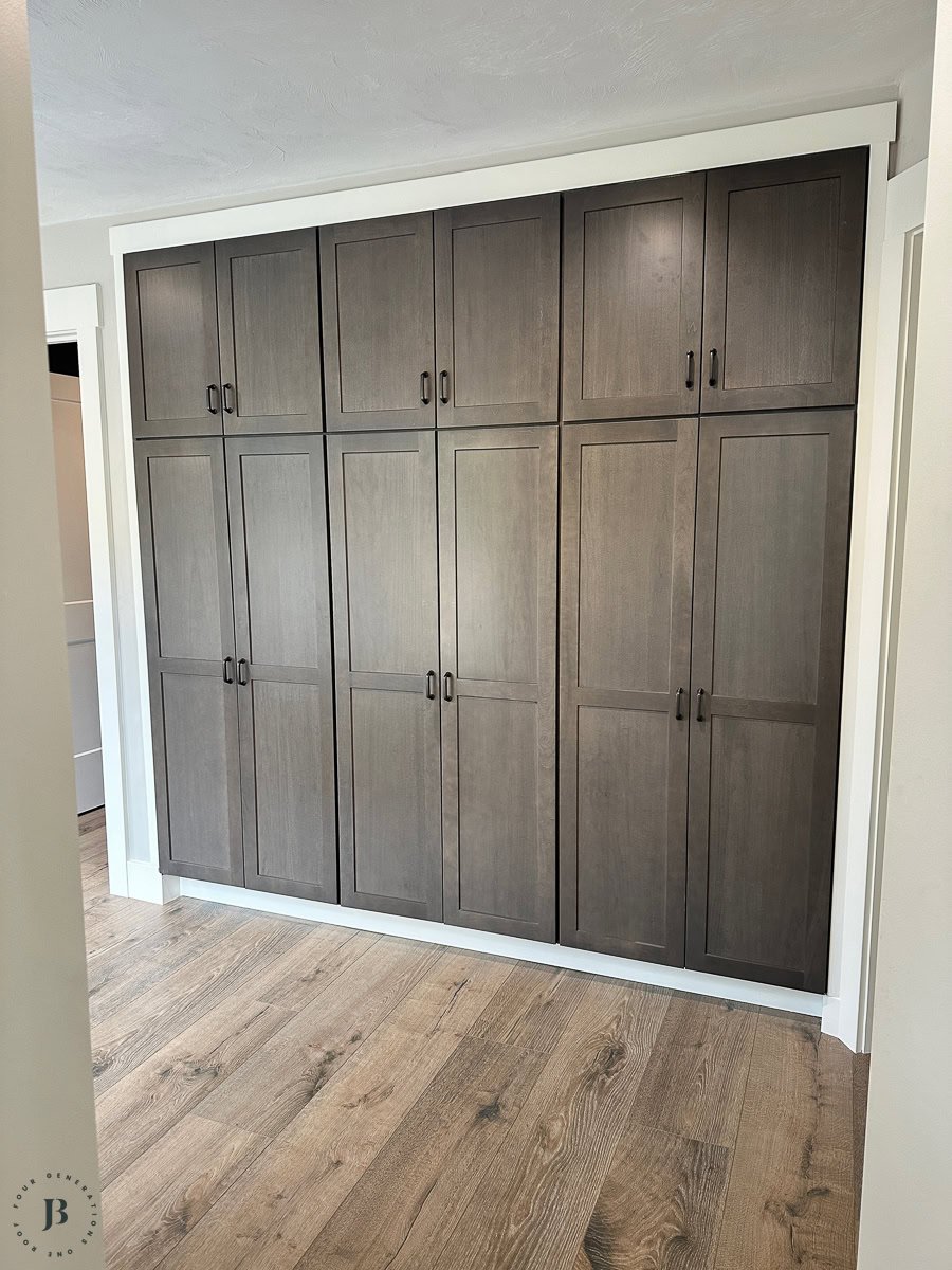 Multigenerational house plans kitchen featuring wide plank flooring and dark brown pantry cabinetry for compound family living