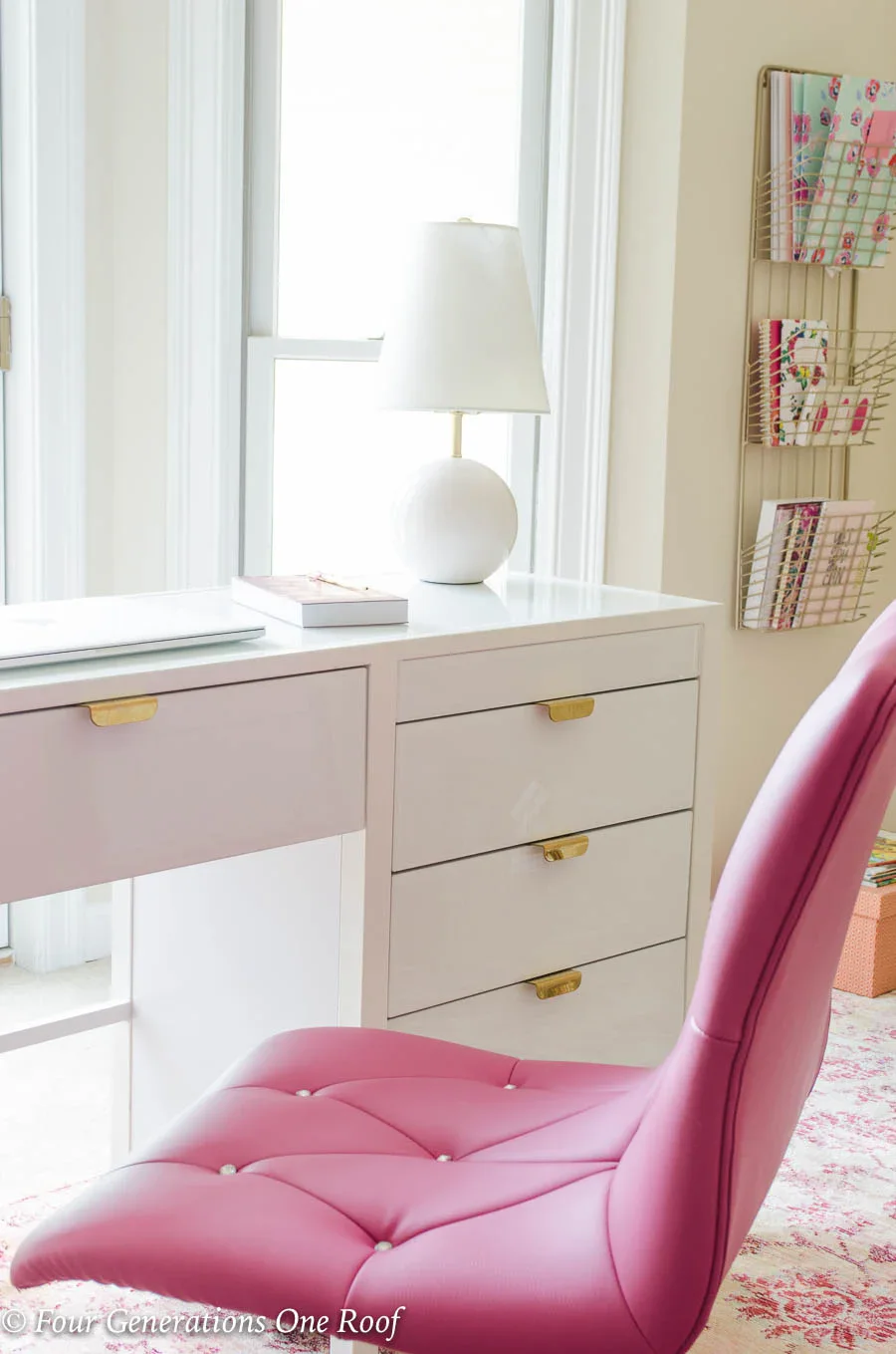 Elegant home office with pink chair, white and gold desk, and pink rug showing girly workspace design