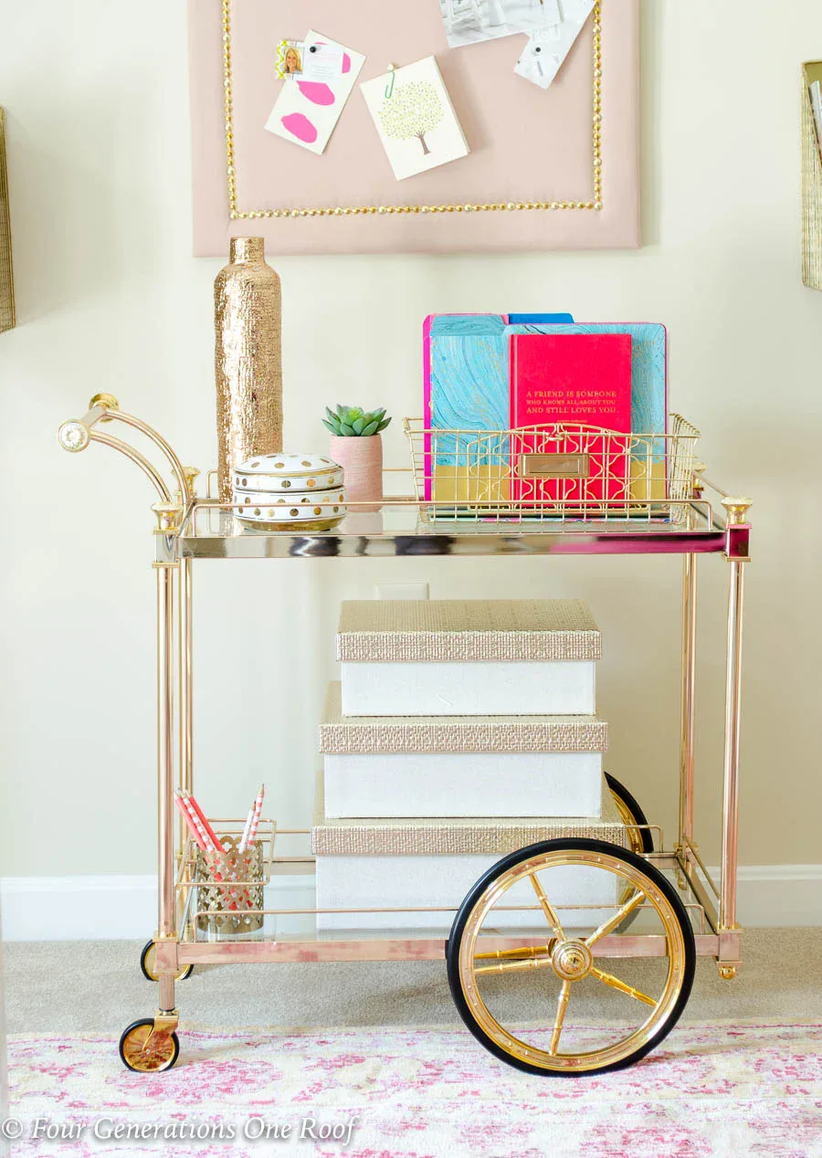 Gold and blush bar cart used for office storage with decorative boxes and filing system